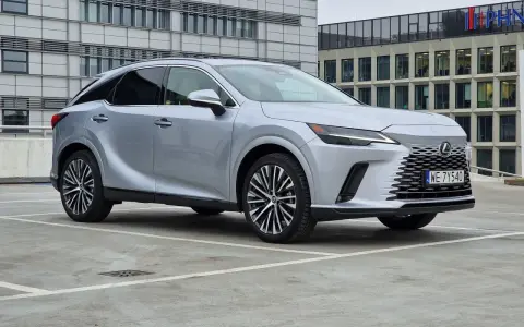 Srebrny Lexus RX 350h zaparkowany przed nowoczesnym budynkiem biurowym.
