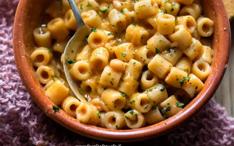 Un piatto fumante di pasta e fagioli, con ditalini e fagioli borlotti in un sugo cremoso, guarnito con prezzemolo tritato.