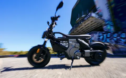 Czarny bmw skuter elektryczny w ruchu, z rozmytym tłem i graffiti.