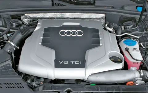 Silnik V6 TDI Audi z widocznym logo i oznaczeniem pojemności. Widać elementy układu dolotowego i płyny eksploatacyjne.