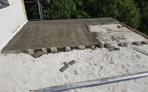 Budowa dachu płaskiego. Wylewanie warstwy styrobetonu, widoczne narzędzia i elementy konstrukcyjne. Prawidłowe proporcje styrobetonu kluczowe dla izolacji.