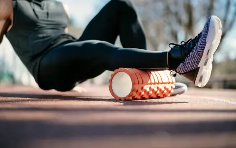 Sportler nutzt eine Faszienrolle vor oder nach dem Training zur Regeneration der Beinmuskulatur.