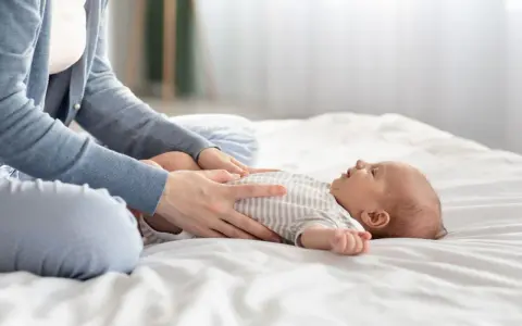 Mama masuje brzuszek niemowlaka, łagodząc bulgotanie w brzuchu i bolesne gazy.