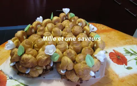 Magnifique chou pièce montée, un délice pour les yeux et les papilles, ornée de fleurs blanches et de feuilles vertes.