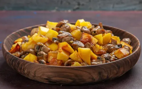Un delicioso salteado de setas y patatas doradas en un cuenco de madera.