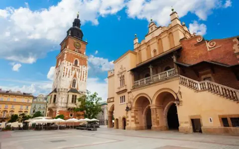 Wieża ratuszowa Kraków na Rynku Głównym, obok Sukiennic. Słoneczny dzień, błękitne niebo z chmurami.