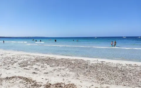 Spiaggia di Arbatax con sabbia chiara e mare cristallino, bagnanti e barche all'orizzonte. Un angolo di paradiso che ricorda la spiaggia rosa.