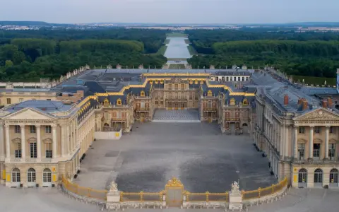Le château de Versailles, construit par Louis XIV, s'étend majestueusement avec ses cours pavées et ses jardins.