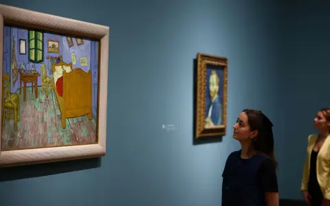 Deux femmes contemplent des tableaux. À gauche, la chambre de Van Gogh, une œuvre iconique dont le prix tableau peinture à l'huile fascine.