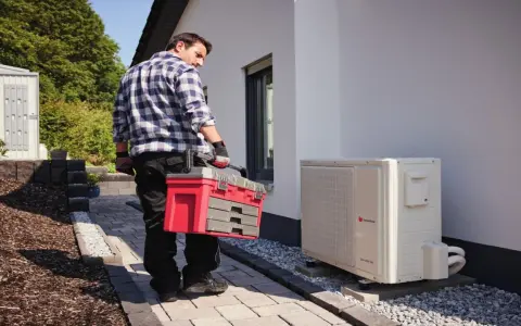Technik z walizką narzędziową przy pompie ciepła. Może sprawdzać kody błędów urządzenia.