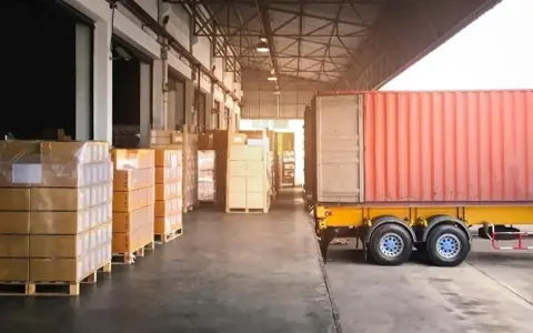 Almacén con camión y contenedores listos para la normativa de carga y descarga de camiones.