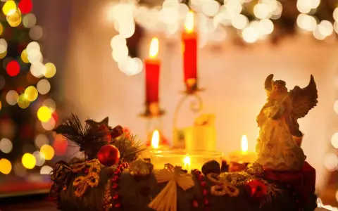 Ein Adventskranz mit Kerzen und einem Engel, umgeben von Weihnachtsbaumlichtern.