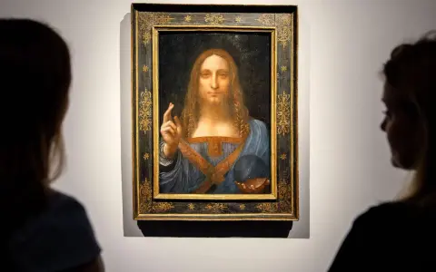 Two viewers admire Leonardo da Vinci's "Salvator Mundi," the most expensive piece of art ever sold, in its ornate frame.