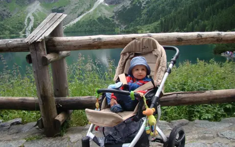Niemowlak w wózku podziwia Tatry. Piękny widok na jezioro i góry.