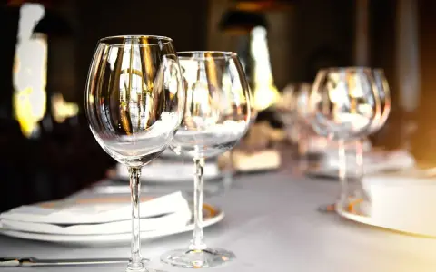Verres à vin vides sur une table dressée, prêts pour un repas. L'emplacement verre table est soigné, reflétant la lumière ambiante.