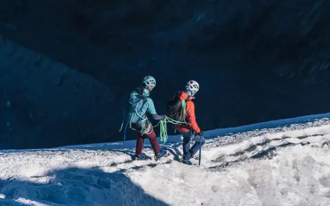 Dwóch alpinistów z raki i czekanami na lodowcu, przygotowuje się do wspinaczki.