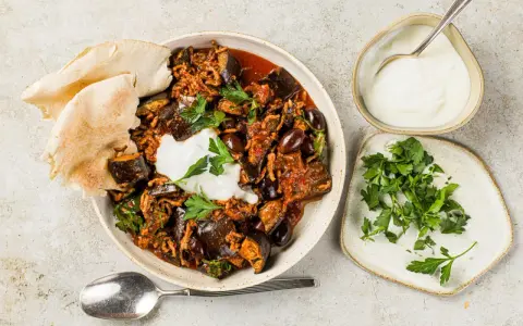 Délicieuse recette aubergine viande hachée, servie avec du pain pita, une cuillère de yaourt et du persil frais.