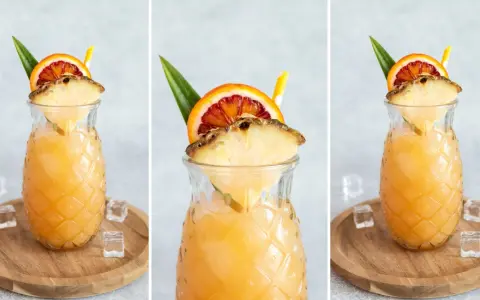Orzeźwiający drink z ananasem i pomarańczą w szklance w kształcie ananasa, ozdobiony owocami i słomką.
