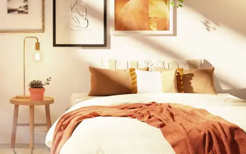 Acogedora habitación con decoración nórdica, cama con mantas y cojines cálidos, mesita de noche con planta y lámpara, y cuadros en la pared.