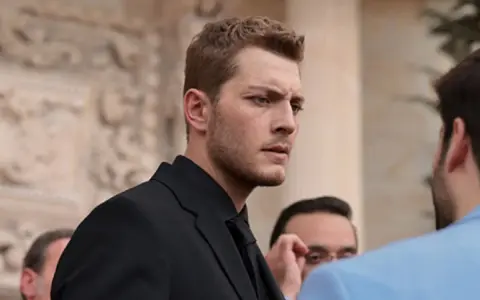 Francesco Montanari, con un abito scuro, interpreta un membro della squadra antimafia, con uno sguardo intenso.