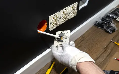 Instalator montuje gniazdko elektryczne. Zastanawiasz się, ile za punkt elektryczny? Widać tu kilka gotowych do podłączenia gniazdek.