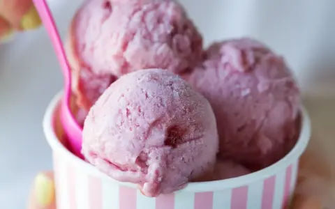 Różowe lody w kubeczku, z różową łyżeczką. Zastanawiasz się, ile kalorii mają lody?
