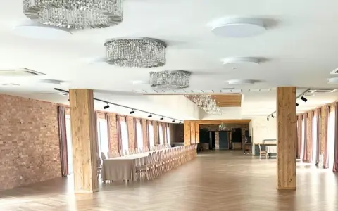Elegancka sala weselna z kryształowymi żyrandolami i długimi stołami. Zastanawiasz się, ile kosztuje wesele na 120 osób w takim miejscu?