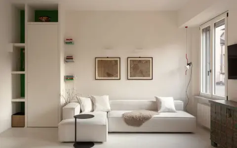 Soggiorno moderno: divano bianco, quadri antichi e libreria a giorno. Idee su come arredare con stile e funzionalità.