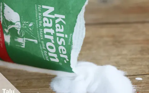 Kaiser Natron wird zum Teppich reinigen mit Natron verwendet. Das weiße Pulver liegt auf Holz.