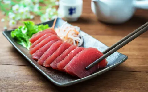 Vackert upplagd tonfisk sashimi på en tallrik, redo att avnjutas med en god vin.