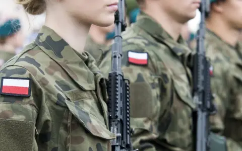 Żołnierze w mundurach z polskimi flagami, gotowi do marszu. Słychać przyśpiewki wojskowe.