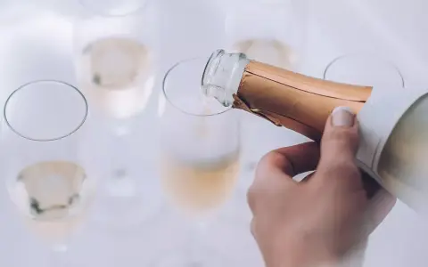 Eine Hand gießt Champagner in ein Glas. Die Bläschen steigen auf und lassen erahnen, wie gut der Champagner schmeckt.