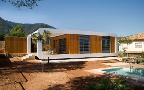 Une maison écologique moderne en bois avec une piscine et une vue sur les montagnes.
