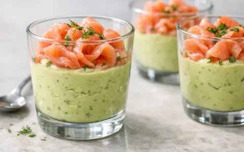 Verrine avocat saumon : une couche crémeuse d'avocat et d'herbes surmontée de fines tranches de saumon fumé, garnie d'aneth.