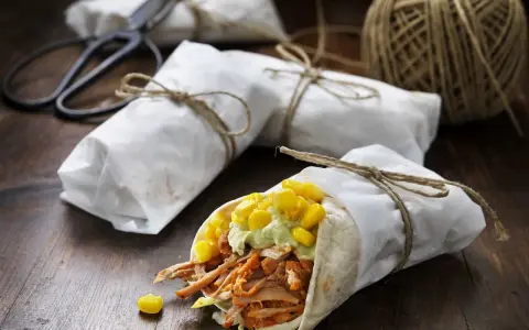 En läcker pulled pork wrap med majs och avokadokräm, inslagen i papper och bunden med snöre.