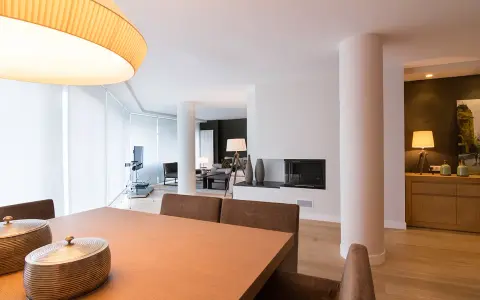 Comedor y salón modernos tras reforma piso pequeño. Mesa de madera, chimenea y mobiliario elegante.
