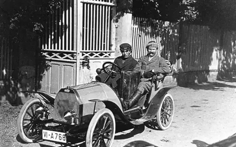 Zwei Männer in einem Bugatti, der aus Molsheim stammt, fahren durch eine sonnige Straße.