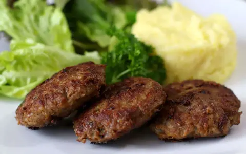 Drei gebratene Fleischpflanzerl mit Kartoffelbrei und Salat. Ein leckeres Fleischpflanzerl Rezept für zu Hause.