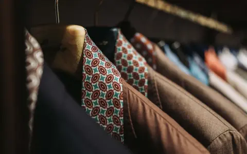 Un guardaroba elegante con giacche marroni e camicie dal tessuto dalle tinte diverse e vivaci, con fantasie geometriche.