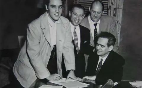 Elvis Presley unterschreibt Dokumente, ein wichtiger Schritt für seinen späteren Elvis Presley net worth.
