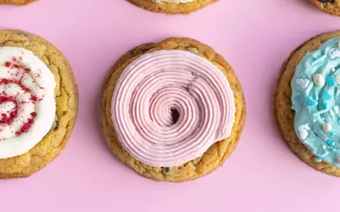 Galletas americanas decoradas con glaseado rosa, blanco con frambuesa y azul con chispas. ¡Una deliciosa receta para compartir!
