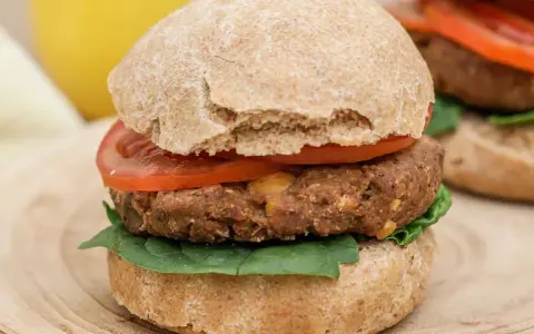Hamburguesa de legumbres con pan integral, tomate y espinacas.