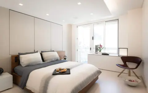 Camera da letto moderna con letto king-size, pannelli imbottiti e soffitto con faretti e strisce led controsoffitto che creano un'atmosfera rilassante.