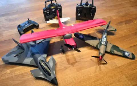 Mehrere ferngesteuerte Flugzeuge, darunter ein rotes Kunstflugmodell und ein Tarnkappenbomber, liegen bereit, um abzuheben.