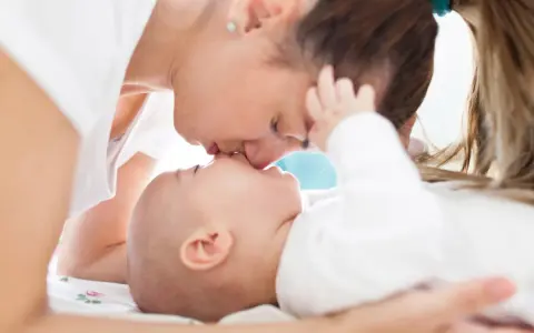 Czuły pocałunek mamy dla jej 3 miesięcznego dziecka.
