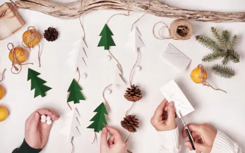 Kinder basteln Weihnachtsgeschenke: Papierbäume, Zapfen und Orangen werden zu einer festlichen Girlande.