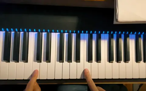 Deux doigts prêts à jouer un accord sur un piano numérique avec des lumières bleues illuminant les touches.