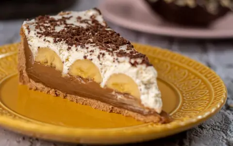 Kawałek banoffee pie z bananami, kremem i czekoladą na żółtym talerzu. Nie tarta cytrynowa, ale pyszny deser!