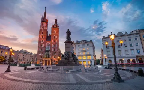 Rynek Główny w Krakowie o zachodzie słońca. Bazylika Mariacka i pomnik Mickiewicza. Ciekawe informacje o Krakowie znajdziesz w tym miejscu.