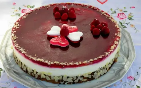 Himbeer Mohn Torte mit frischen Beeren und Herz-Gelees. Ein süßer Genuss für besondere Anlässe.